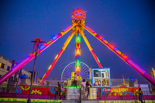 colorful LED lights of pendulum fairground ride shine in the night
